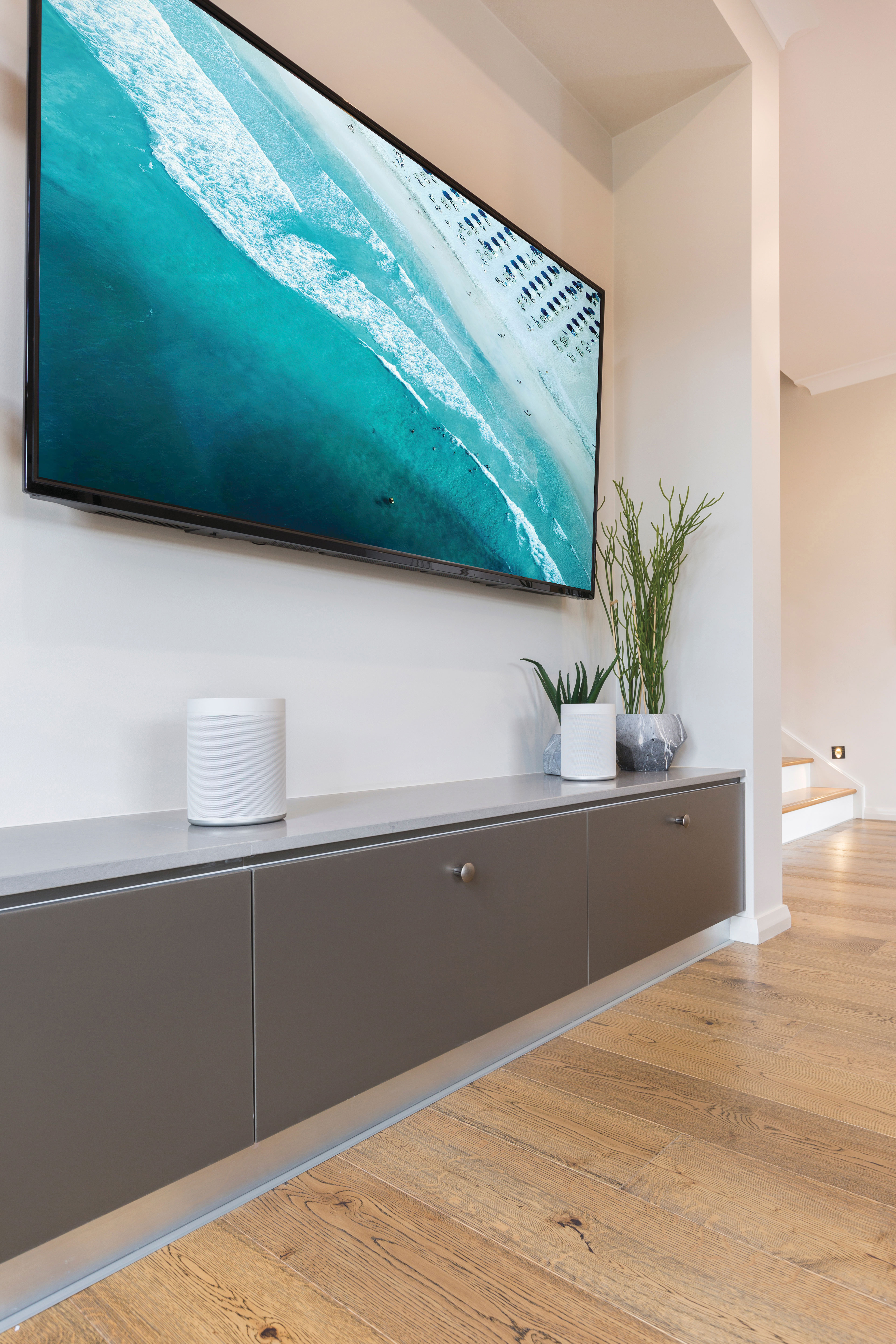 Modernes Wohnzimmer mit Wand-TV, Konsole und Holzböden.