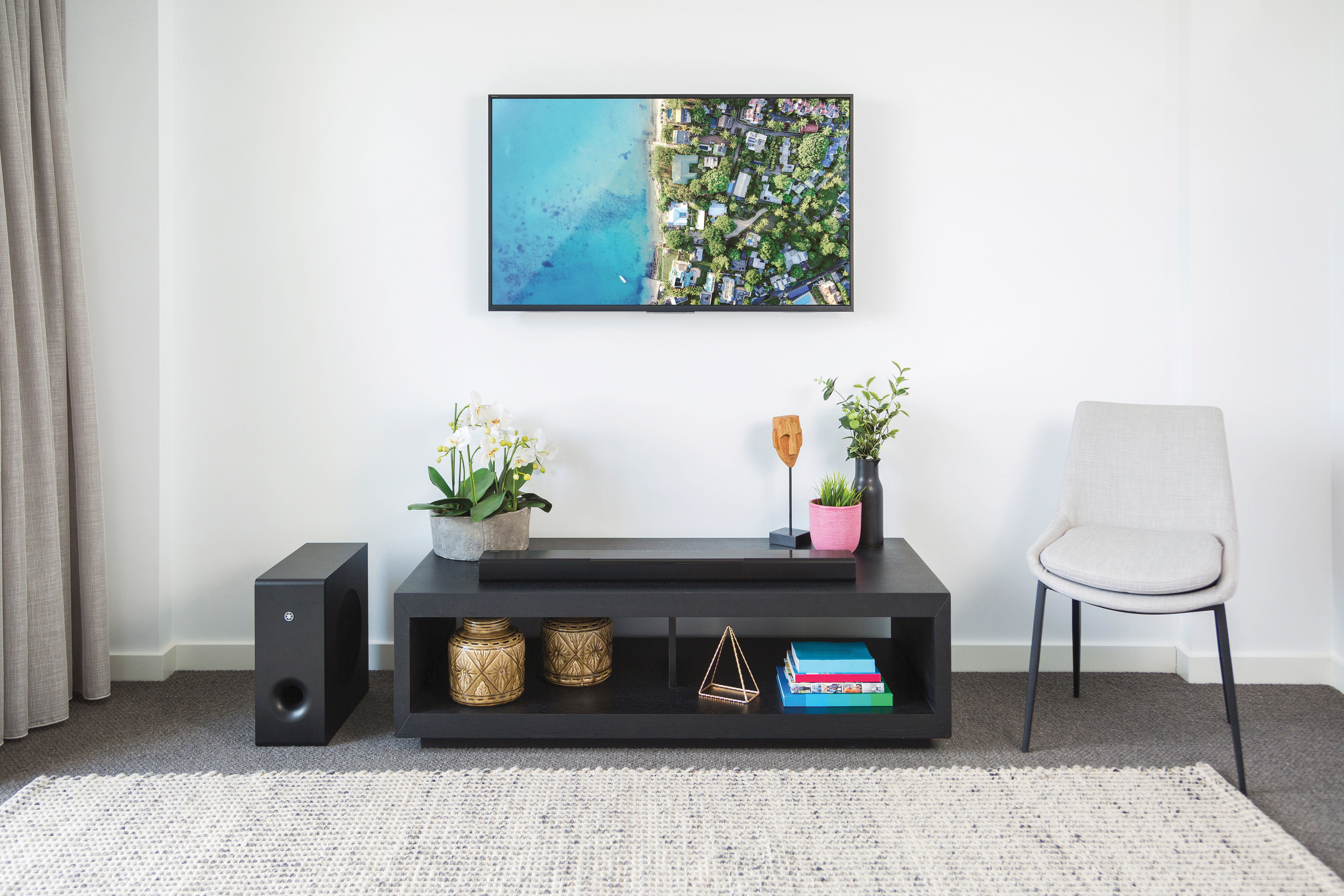 Wohnzimmer mit Fernseher über einem Schrank, einer Soundbar, einem Subwoofer und einem Stuhl.