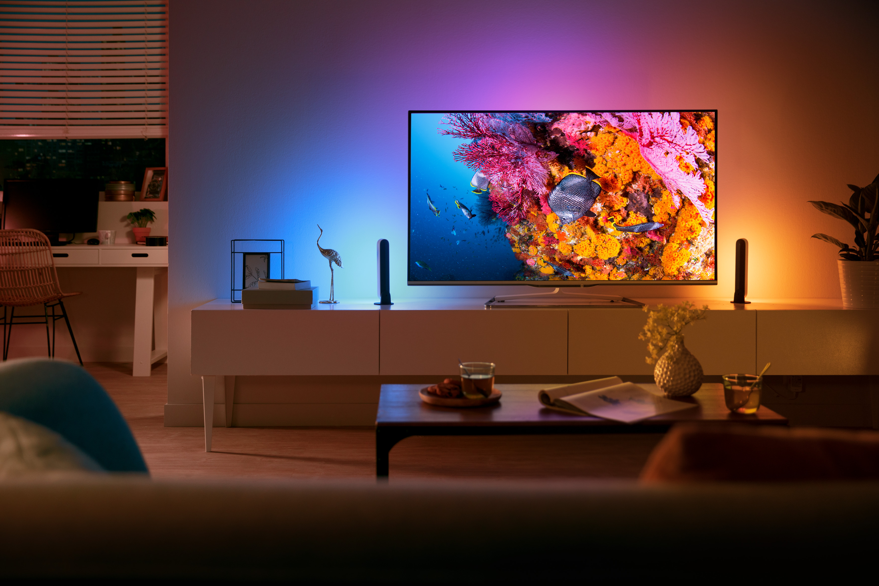Soggiorno con TV che mostra una scena subacquea colorata. Luci colorate sulla parete e sui mobili.