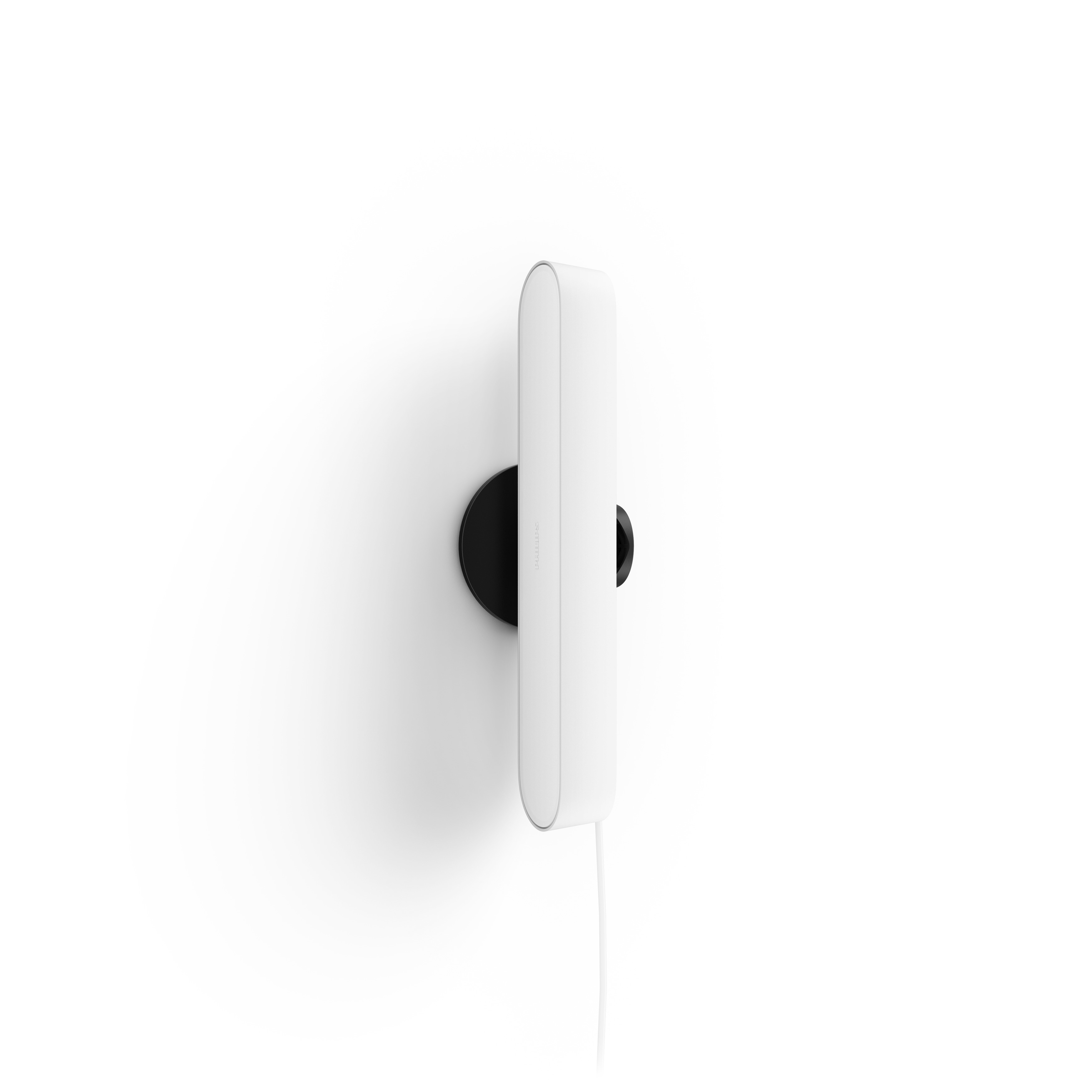 Ein weißes, stromlinienförmiges Wandtelefon auf schwarzem kreisförmigen Sockel, an weißer Wand.