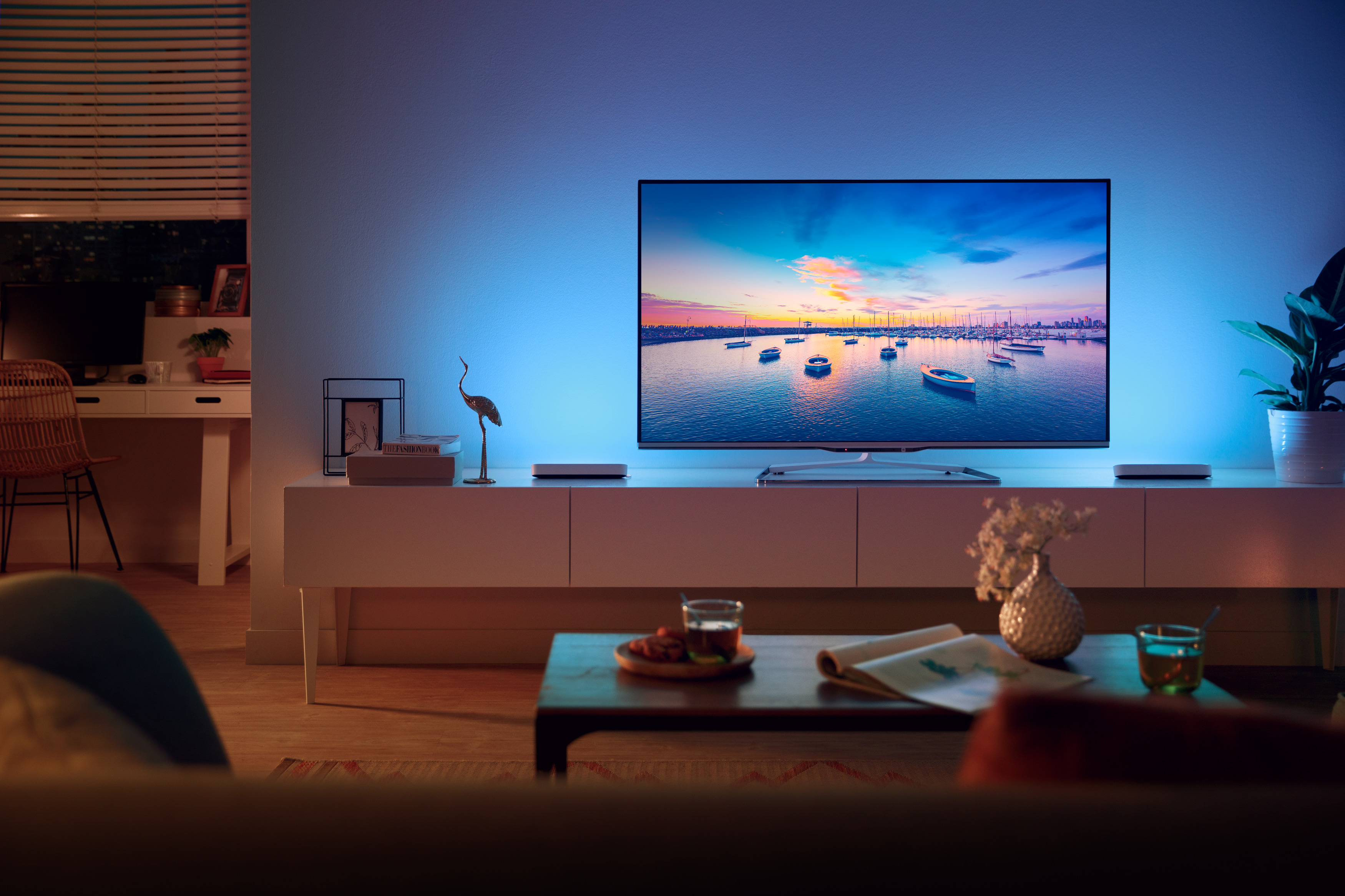 Wohnzimmer mit Fernseher, weißem Schrank und Bootsblick bei Sonnenuntergang.