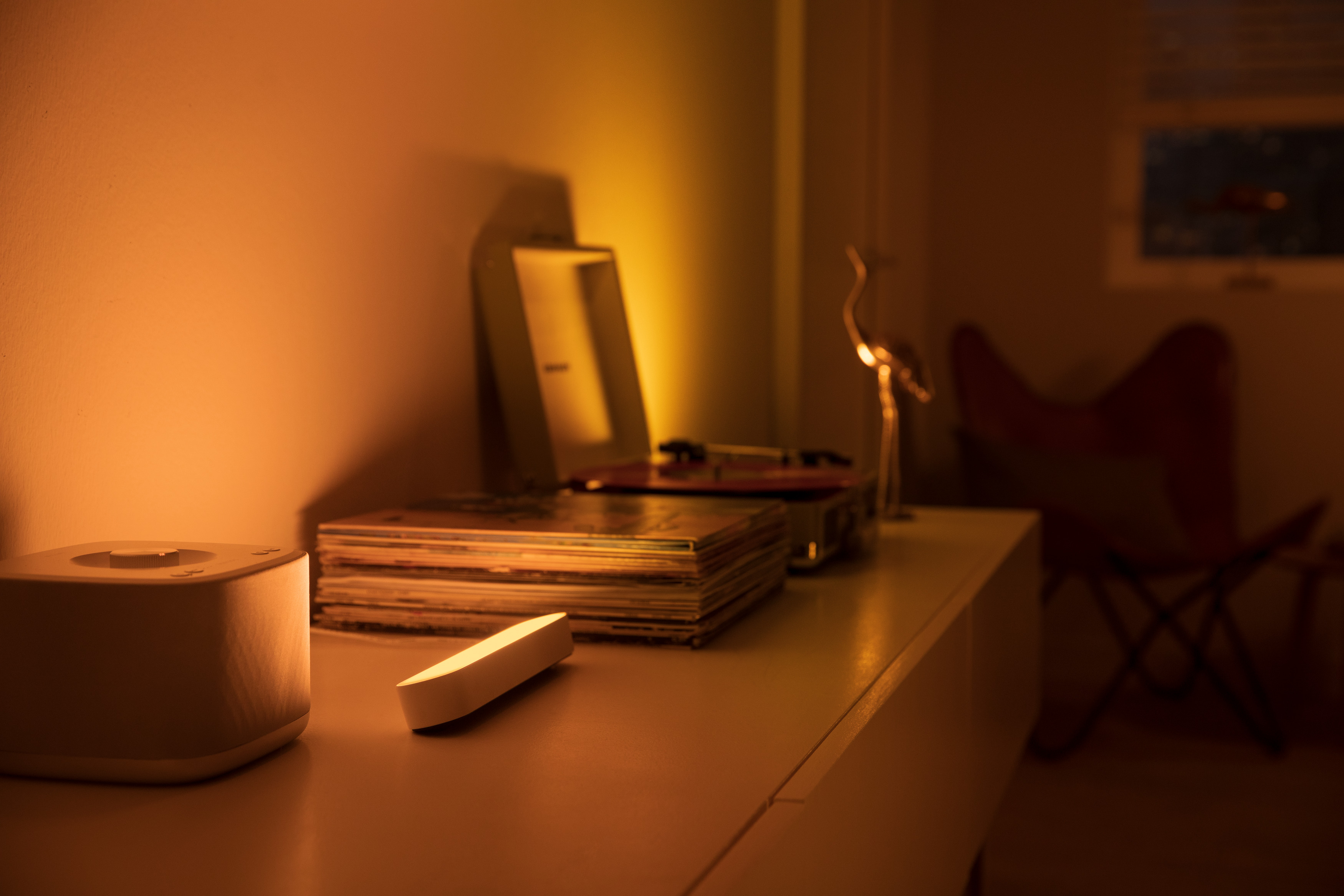 Eine weiße Lampe, ein Plattenspieler, Schallplatten und eine goldene Figur auf einem Tisch.