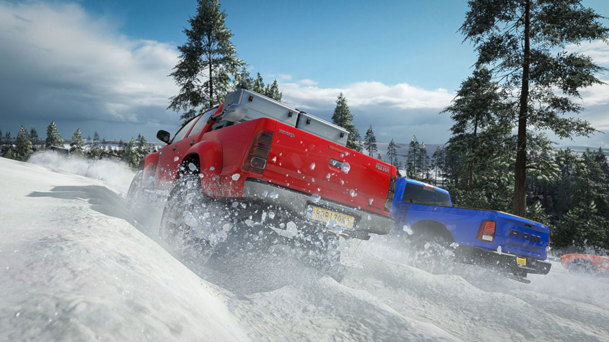 Des camions rouges et bleus roulent dans la neige, soulevant de la neige.