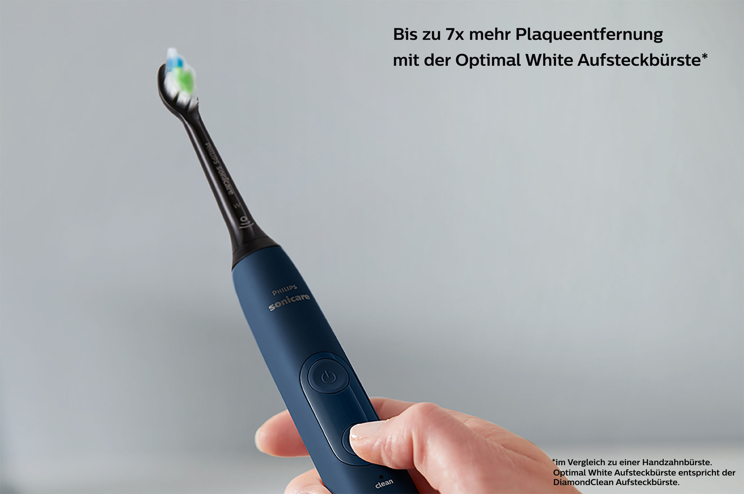 Eine marineblaue elektrische Zahnbürste wird von einer Hand gehalten, mit weißem Hintergrund.