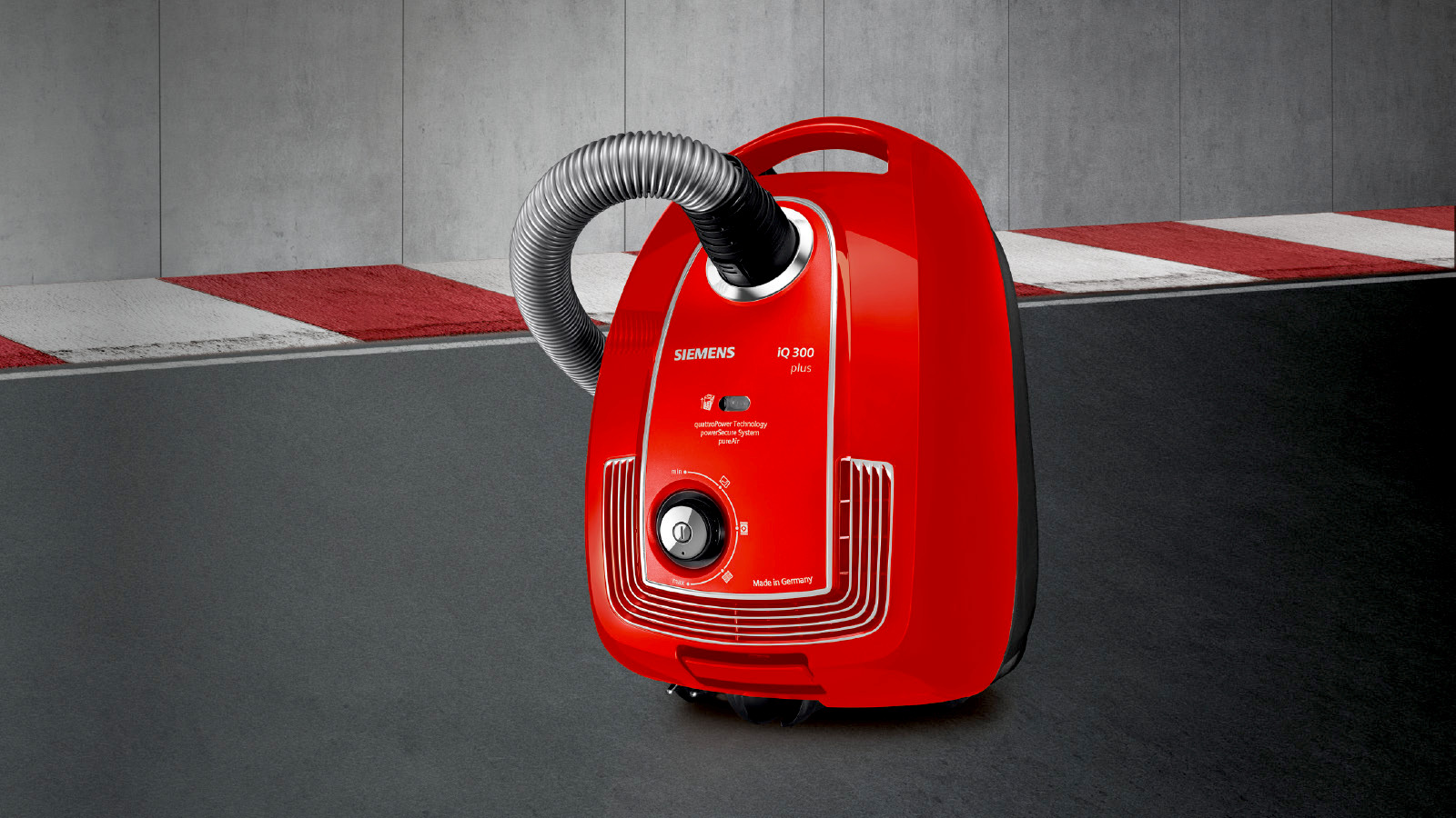 Ein roter SIEMENS Staubsauger mit flexiblem Schlauch auf Rennstreckenhintergrund.