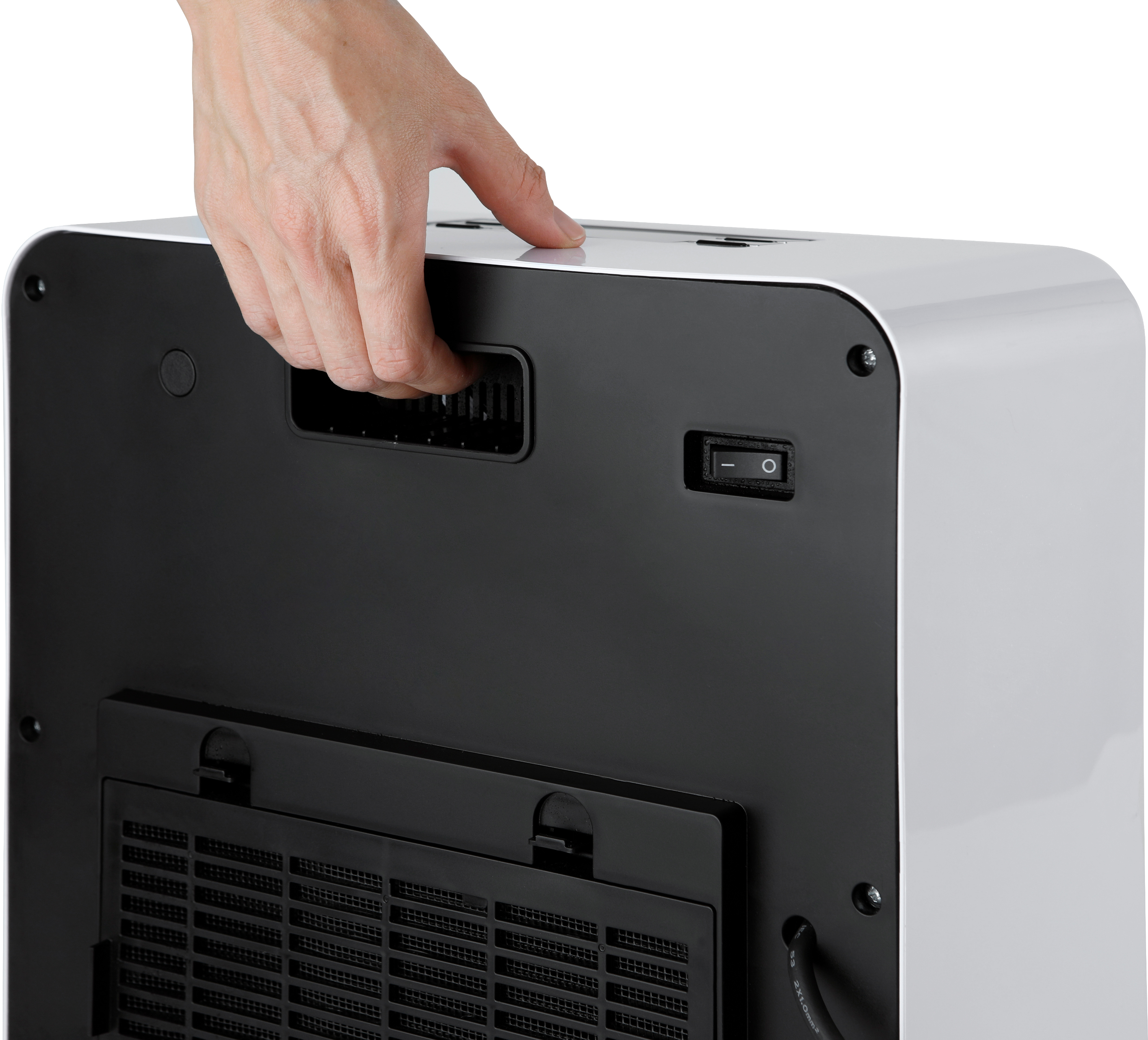 A hand presses a button on the back of a white and black device, likely an air purifier.