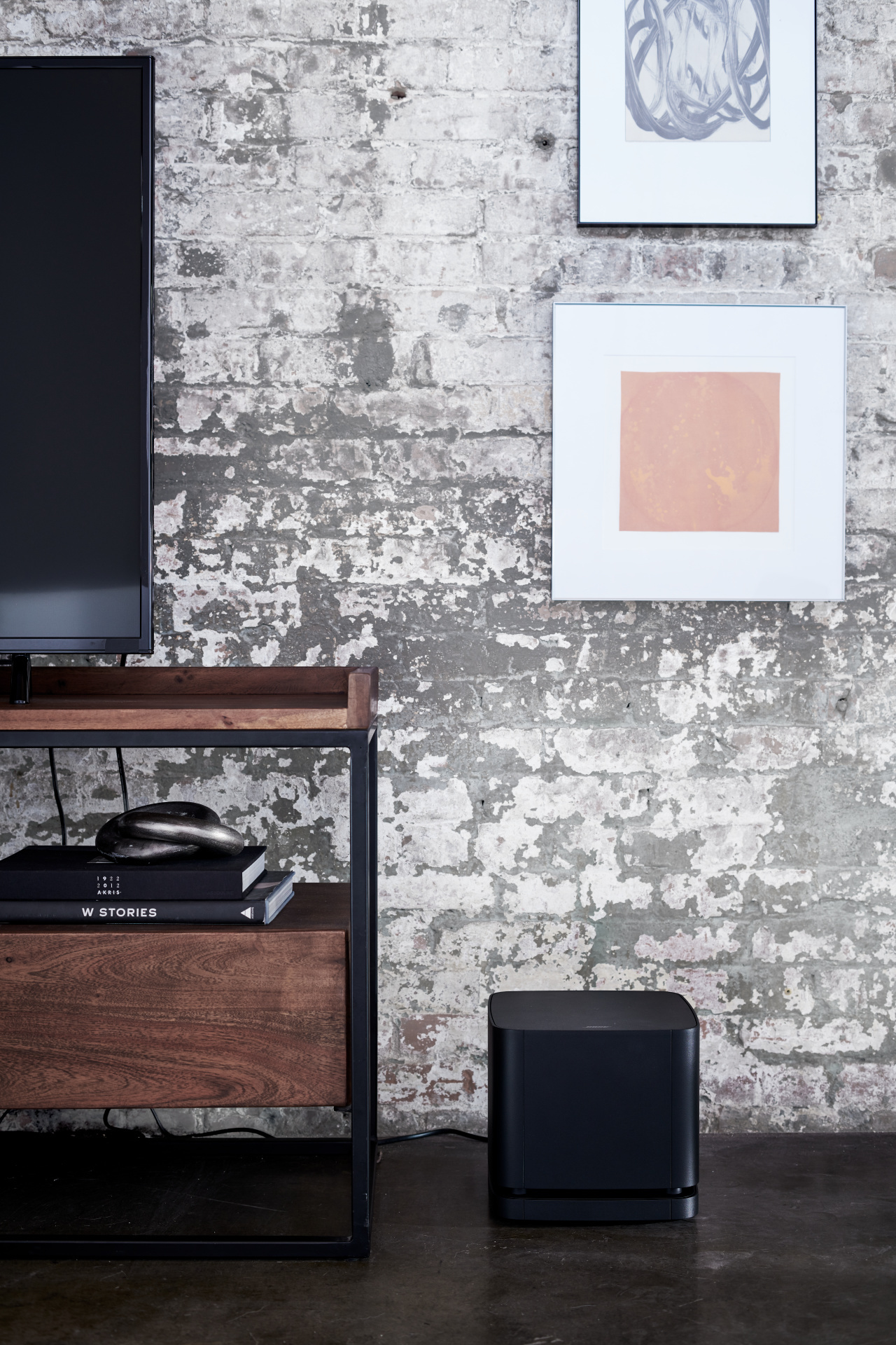 Wohnzimmer-Setup. Schwarzer Lautsprecher, Holzschrank, Kunst an der Wand, Betonboden.