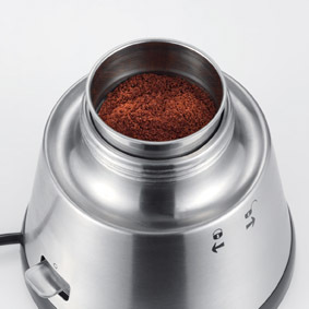 Eine Kaffeemühle aus Edelstahl mit gemahlenem Kaffee in der oberen Kammer.
