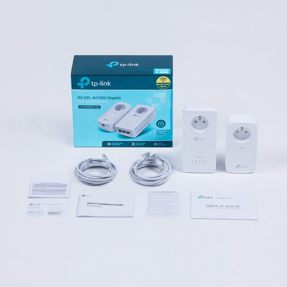 A TP-Link network kit with two powerline adapters, cables, and quick installation guide. White surface.