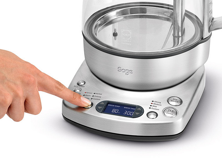 Eine Hand drückt eine Taste auf einem silbernen Wasserkocher mit digitaler Anzeige.