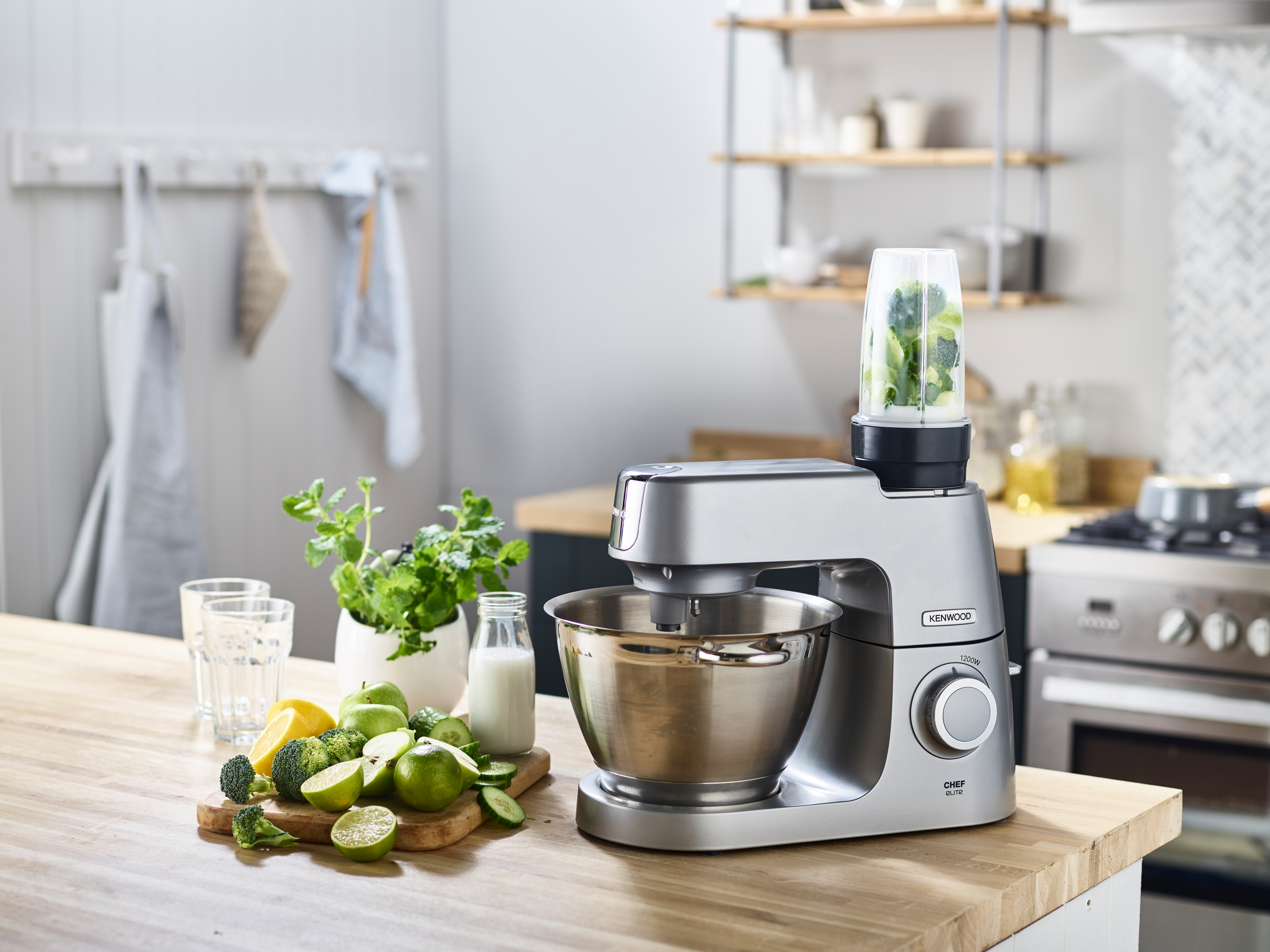Silberner Kenwood-Küchenroboter mit Zutaten auf Holztisch.