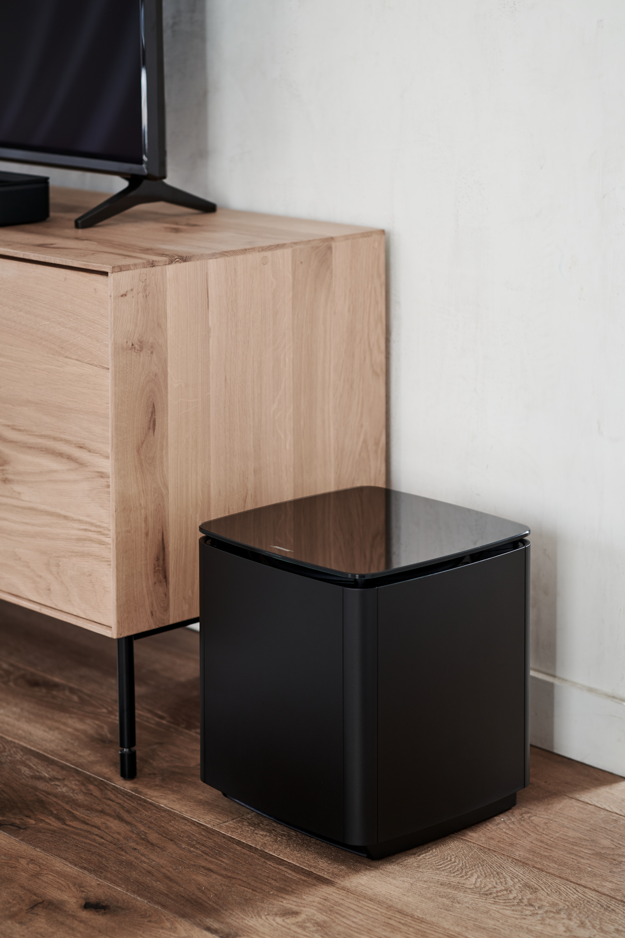 Schwarzer Bose-Subwoofer neben einem Holzschrank.