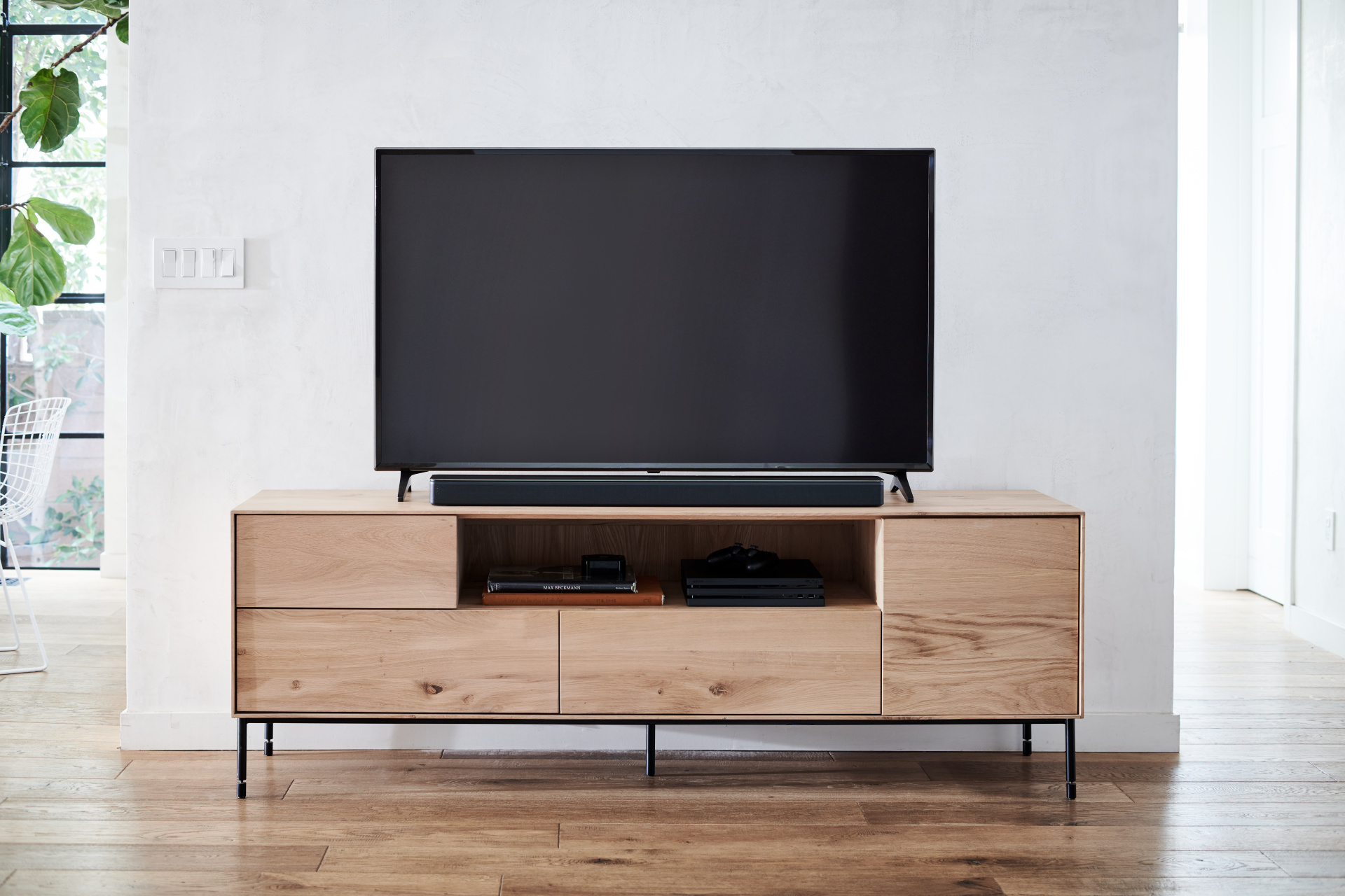 Moderner TV-Ständer aus hellem Holz mit TV und Objekten im offenen Fach.