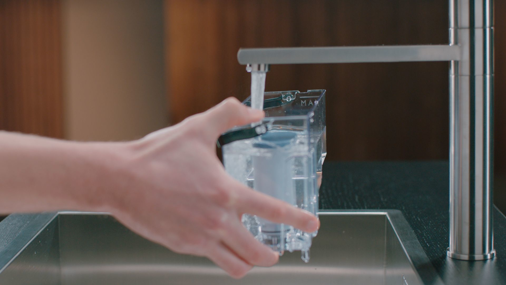 Personne remplissant un réservoir d'eau à partir d'un robinet, l'eau coule dans le récipient.