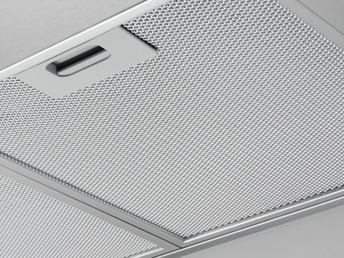 Close-up of a silver range hood filter, with a grid pattern and a handle.