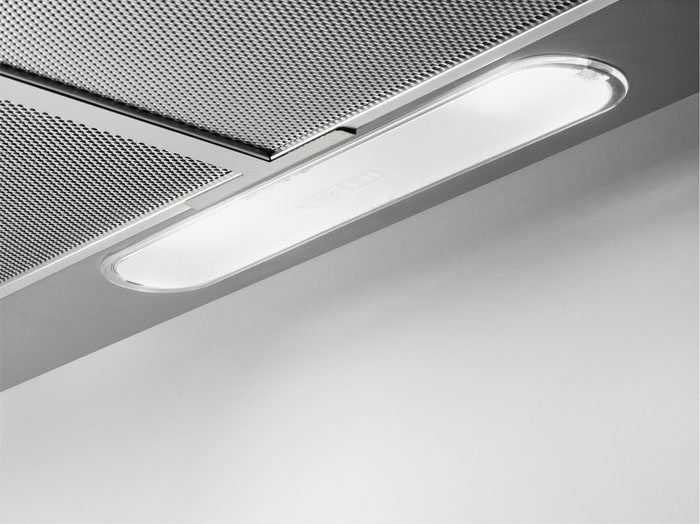 Underside of a stainless steel range hood with a bright, long, rectangular light fixture.