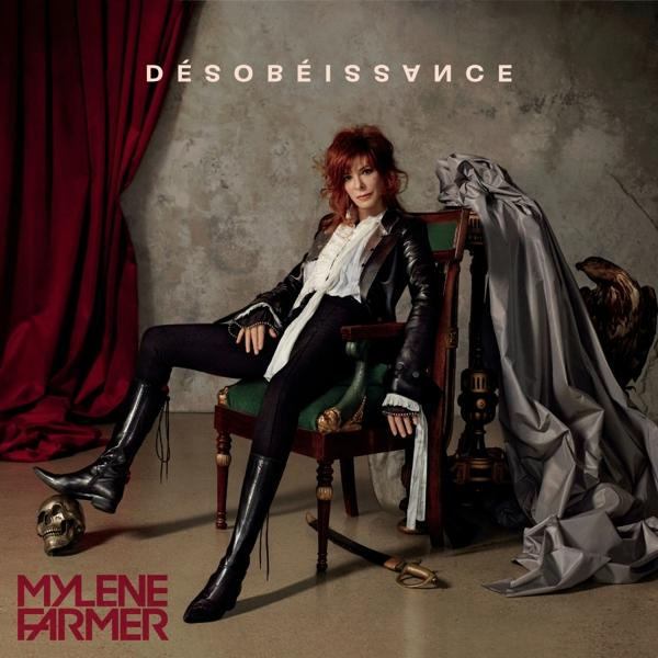 Mylène Farmer zit op een stoel, draagt een zwarte leren jas en laarzen. Een schedel, zwaard en adelaarsbeeld zijn aanwezig.