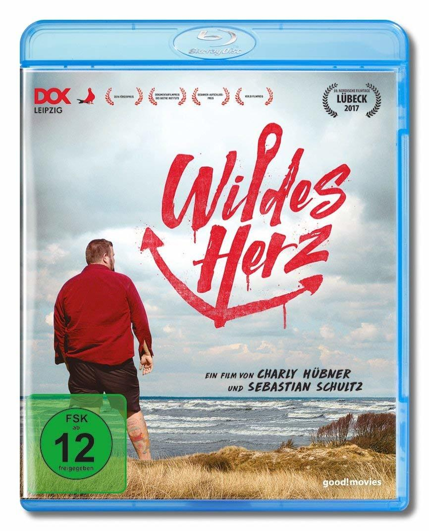 Blu-ray-Cover: Ein Mann im roten Hemd am Strand und der Filmtitel Wildes Herz mit einem Anker.
