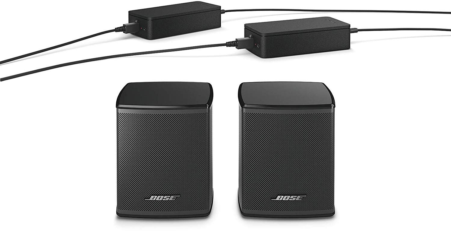 Deux enceintes Bose noires et deux adaptateurs secteur noirs avec câbles noirs sur fond blanc.
