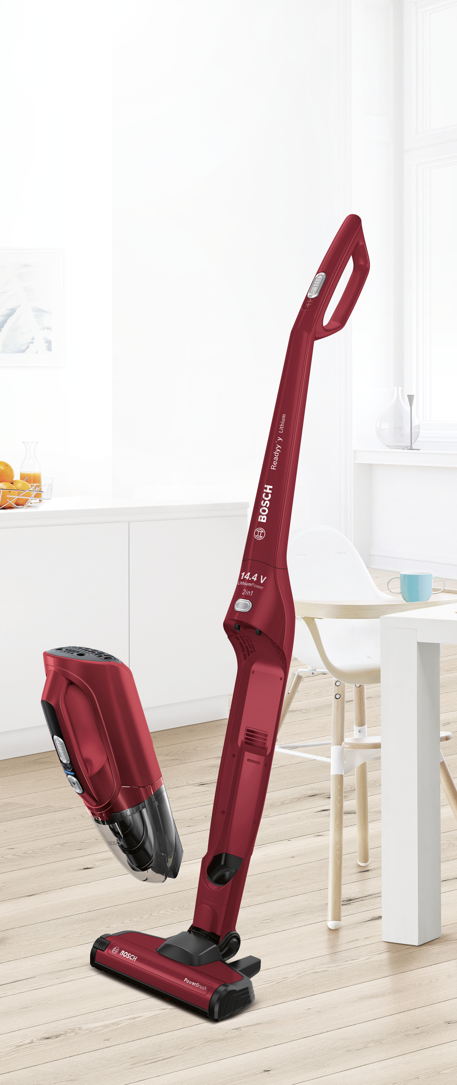 Roter kabelloser Staubsauger und Handteil neben einer Küche.