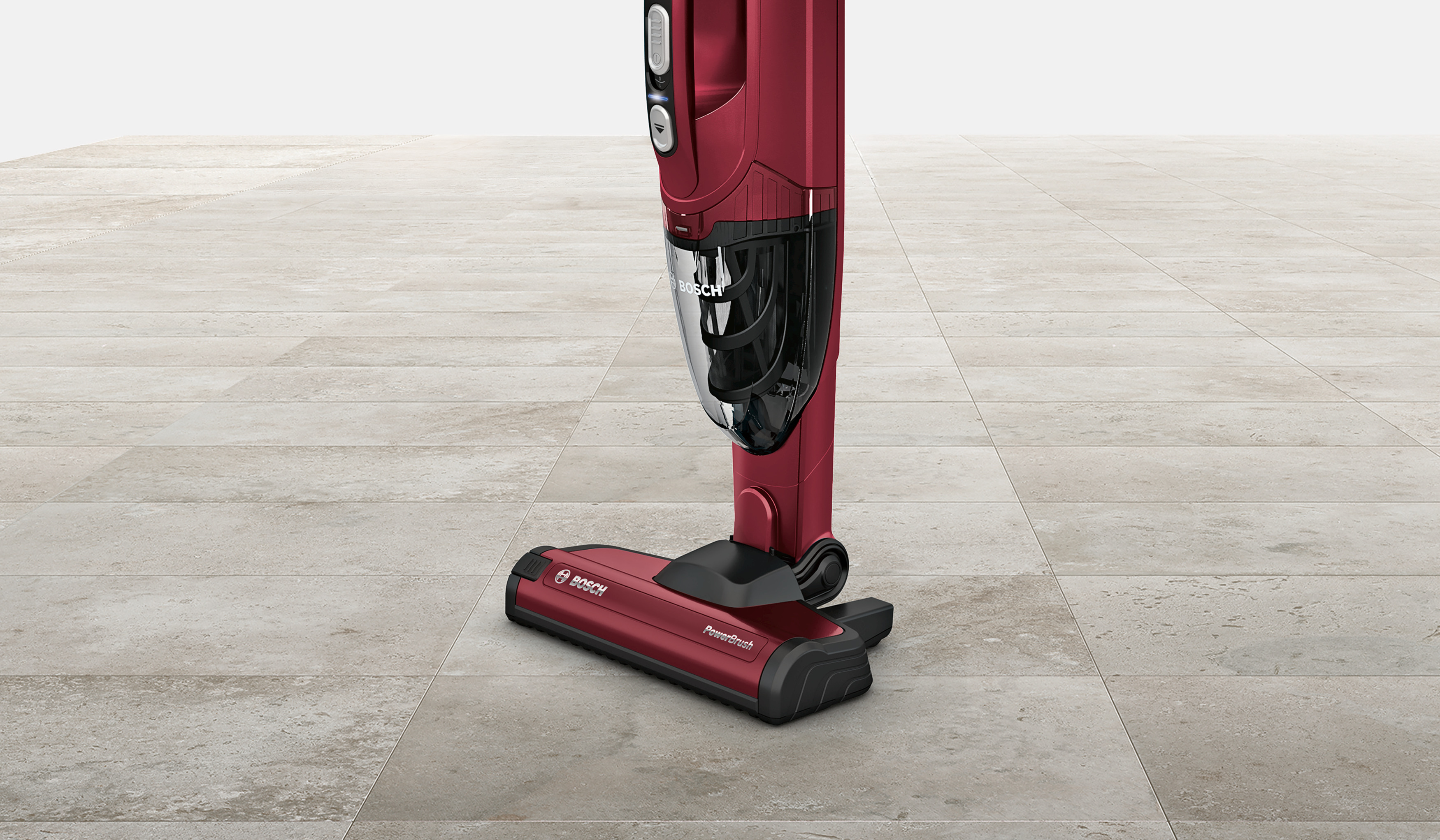 Ein roter Bosch PowerBrush Staubsauger steht auf einem gefliesten Boden. Der Staubsauger ist aufrecht, mit einem durchsichtigen Staubbehälter.