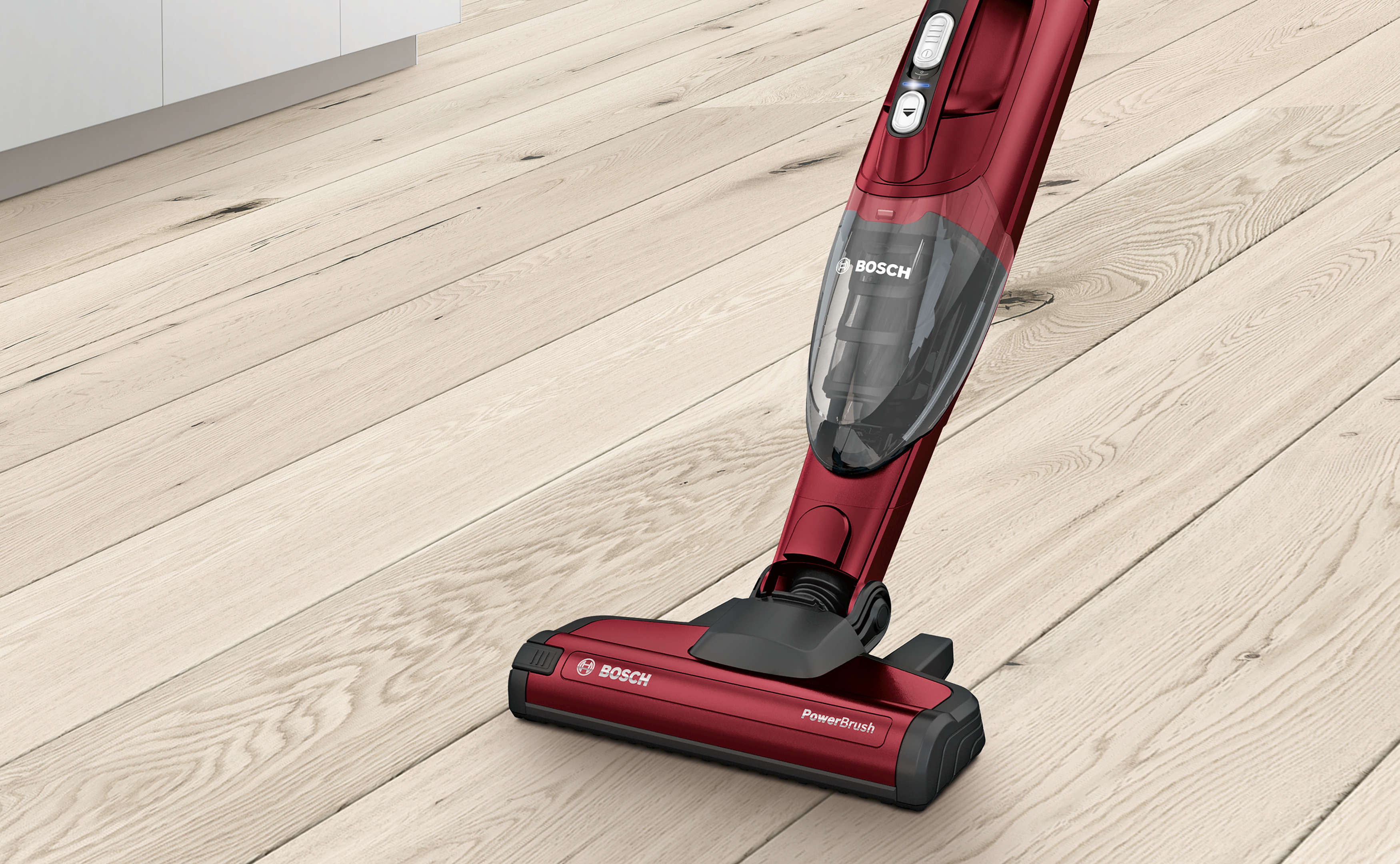 Ein roter, kabelloser Bosch-Staubsauger steht auf einem hellen Holzboden. Der Staubsauger ist abgewinkelt und zeigt Details.