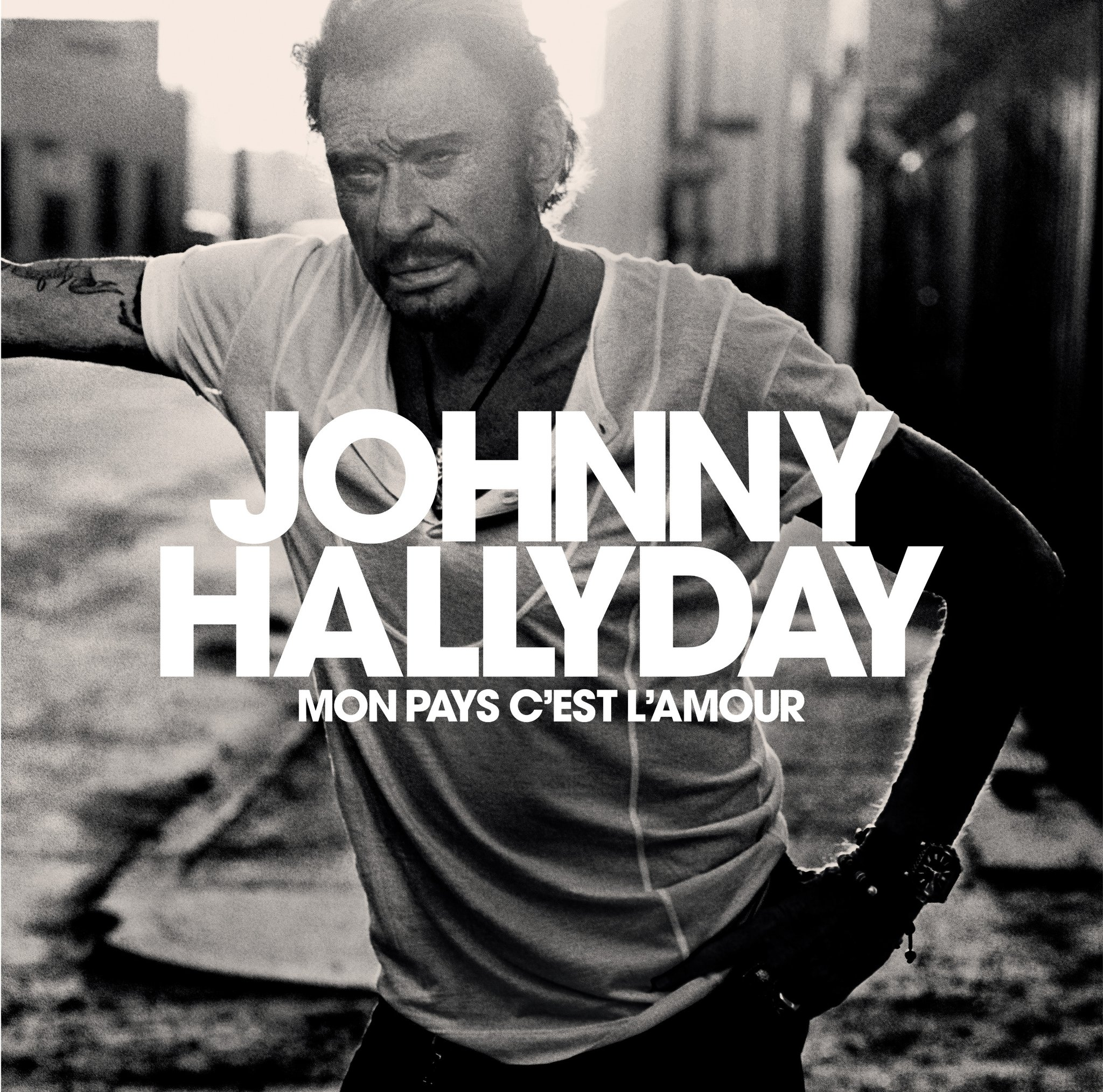 Zwart-witfoto van Johnny Hallyday. Tekst: Johnny Hallyday, Mon pays c'est l'amour.