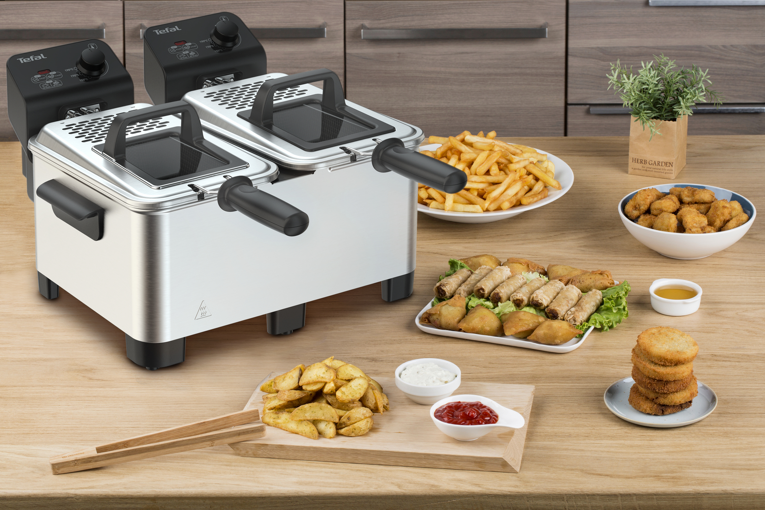 Double fryer with fried food on a wooden table. Fries, spring rolls, and more.