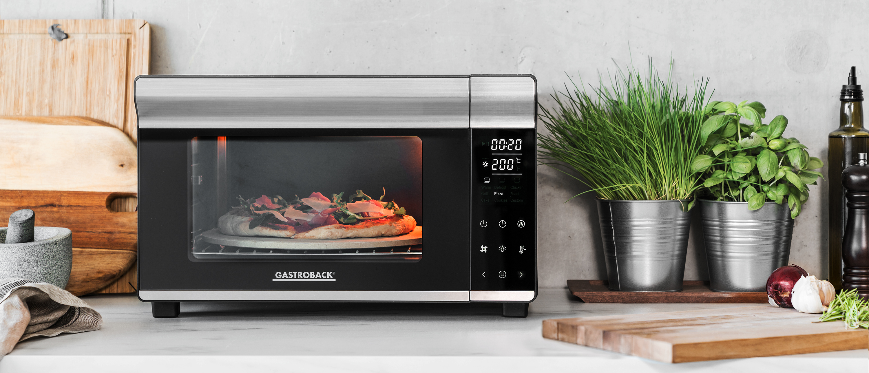 Ein Gastrobak-Ofen mit Pizza, umgeben von Küchenartikeln.