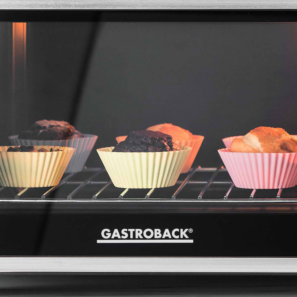 Ein Ofeninnenraum mit Muffins in Papierförmchen, die auf einem Rost backen.