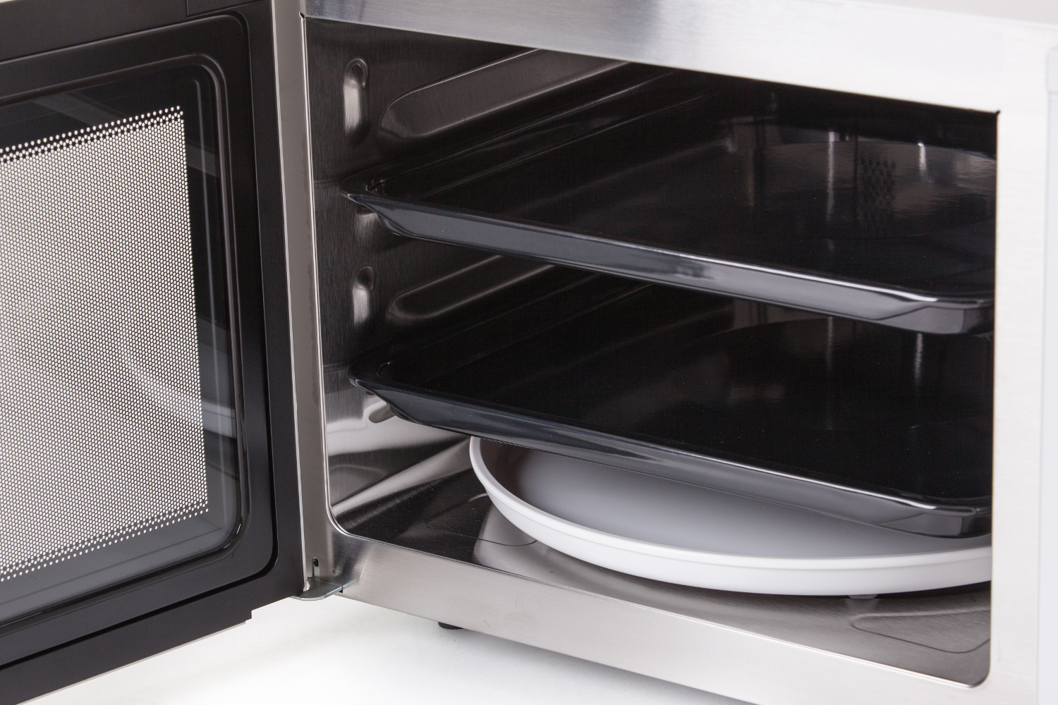 Interior of a microwave oven with trays and a plate. White background.