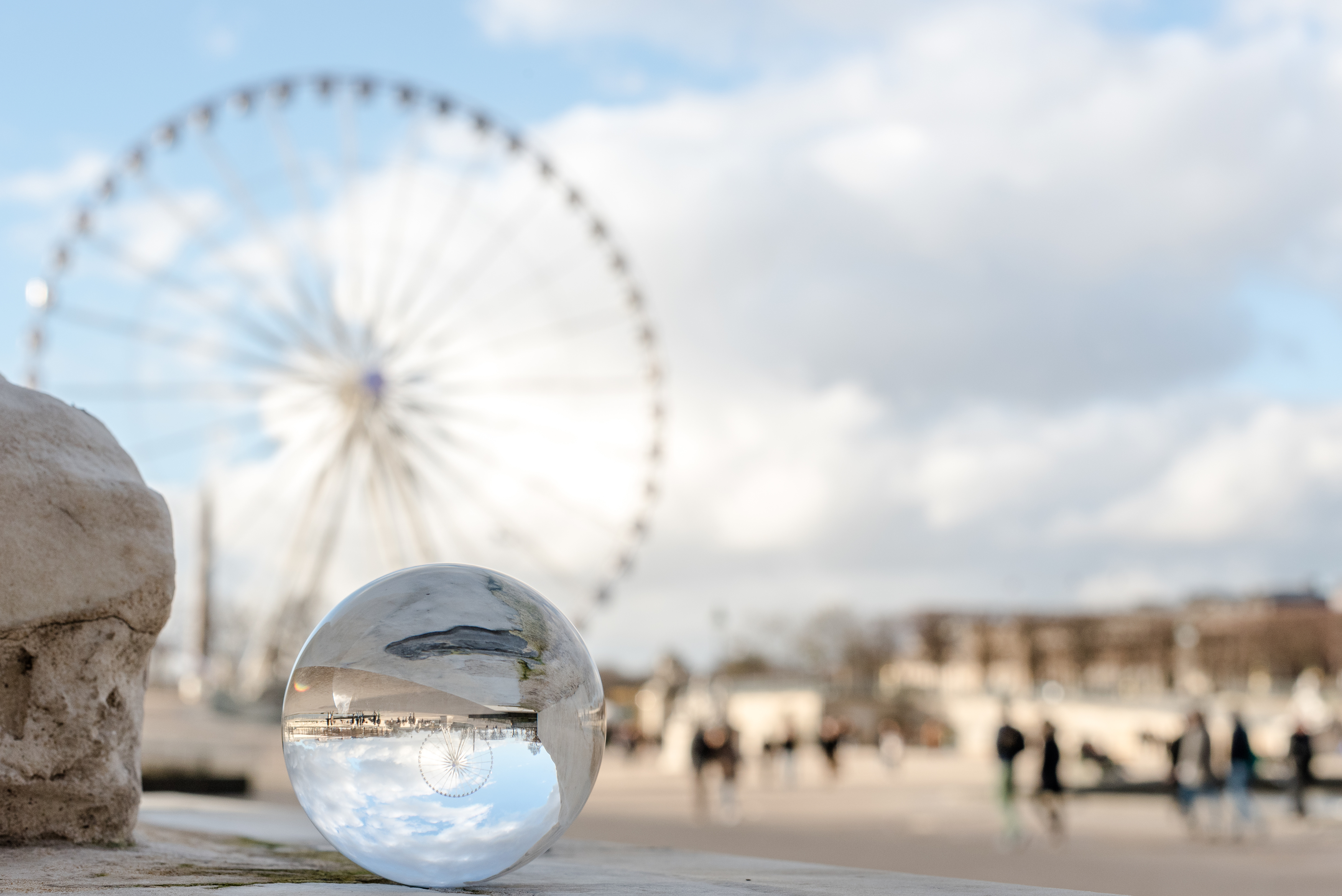 Glaskugel, die eine Stadt mit einem Riesenrad reflektiert.