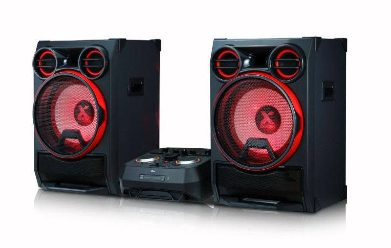 Dos altavoces negros con luces rojas y una consola de DJ entre ellos, todo sobre una superficie blanca.