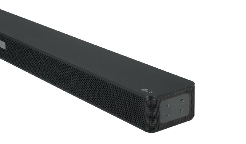 Barra de sonido LG negra. Cuenta con una parte frontal de malla, controles de encendido y volumen. Logotipo de LG a la derecha.