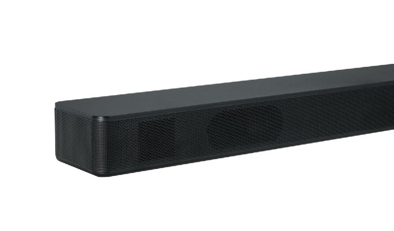 Barra de sonido negra con frontal de malla, vista en ángulo. Forma rectangular.