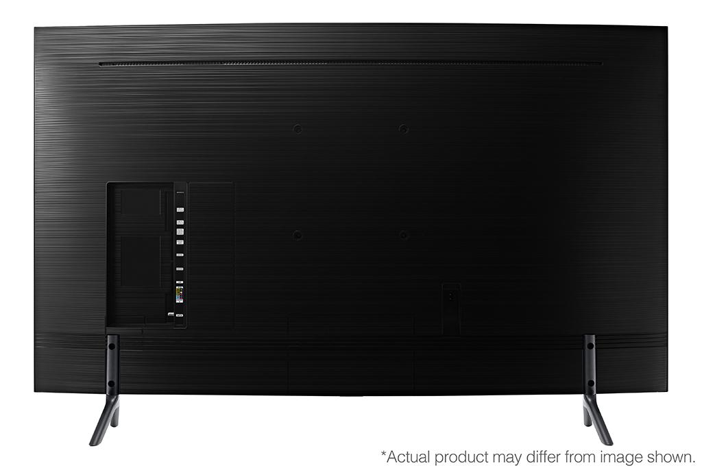 Vista trasera de un televisor negro grande con puertos y soporte. El televisor está sobre una superficie blanca.