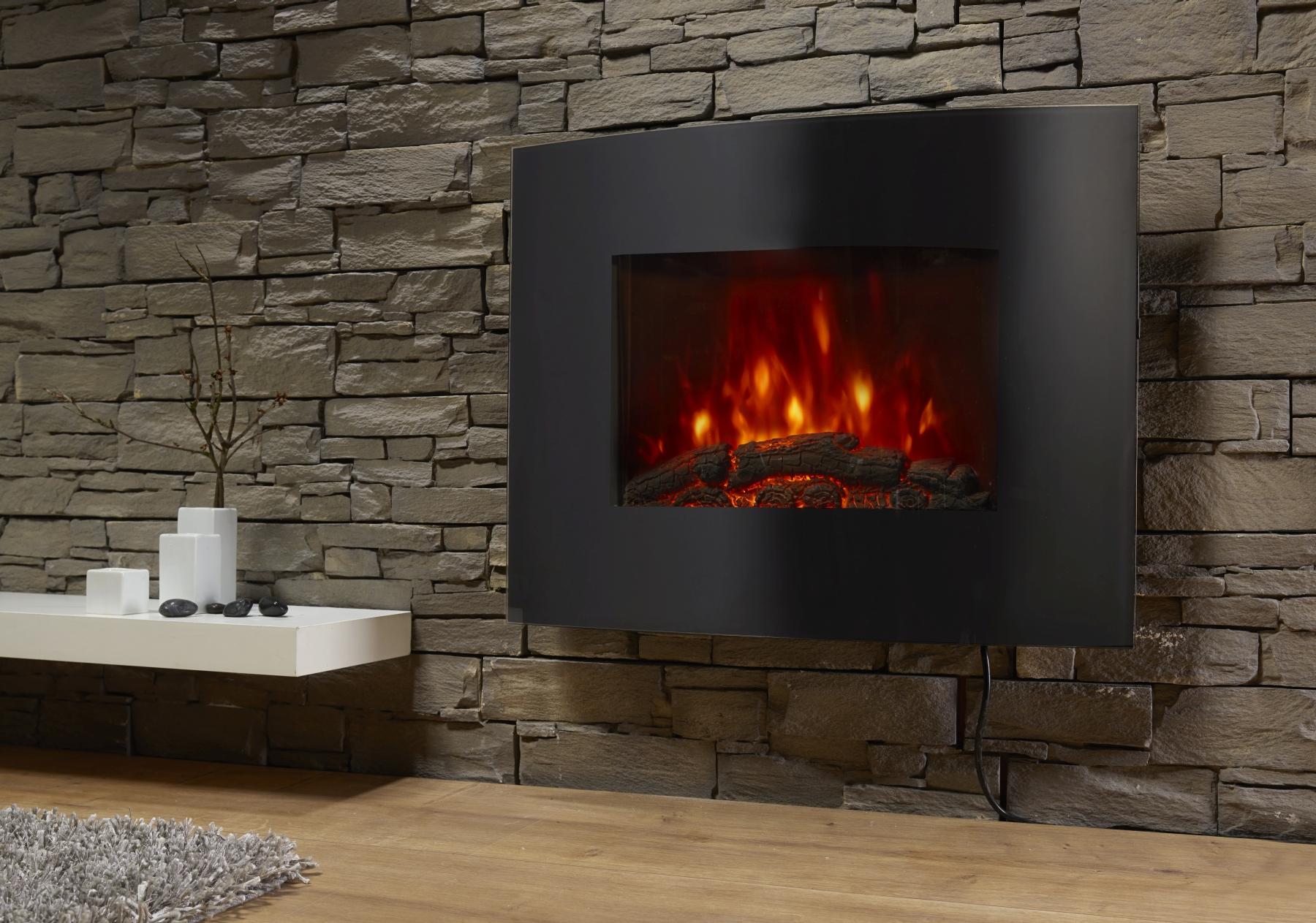 Ein schwarzer, an der Wand montierter elektrischer Kamin mit Steinmauerhintergrund und weißem Regal.