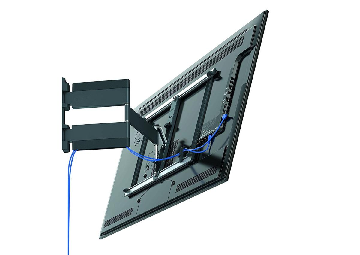 Televisor grande montado en un soporte de pared. Se ven cables azules. Fondo blanco. Vista en ángulo.
