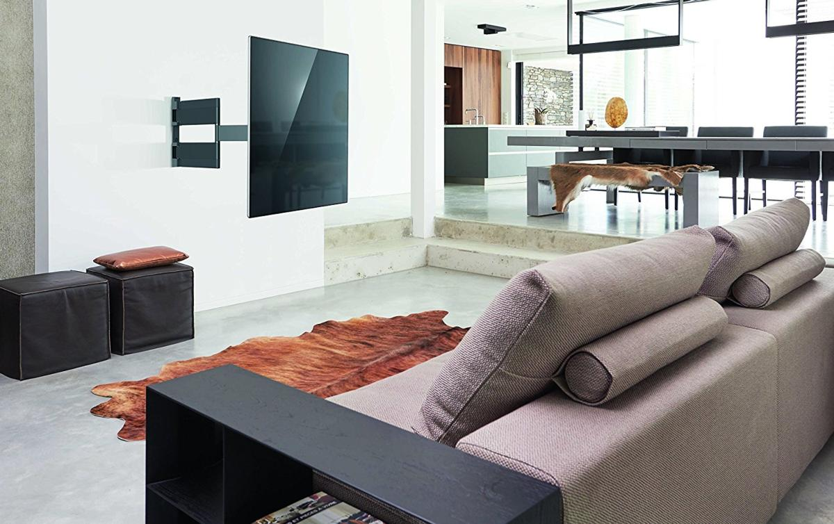 Salón moderno con TV montada y alfombra de cuero marrón.