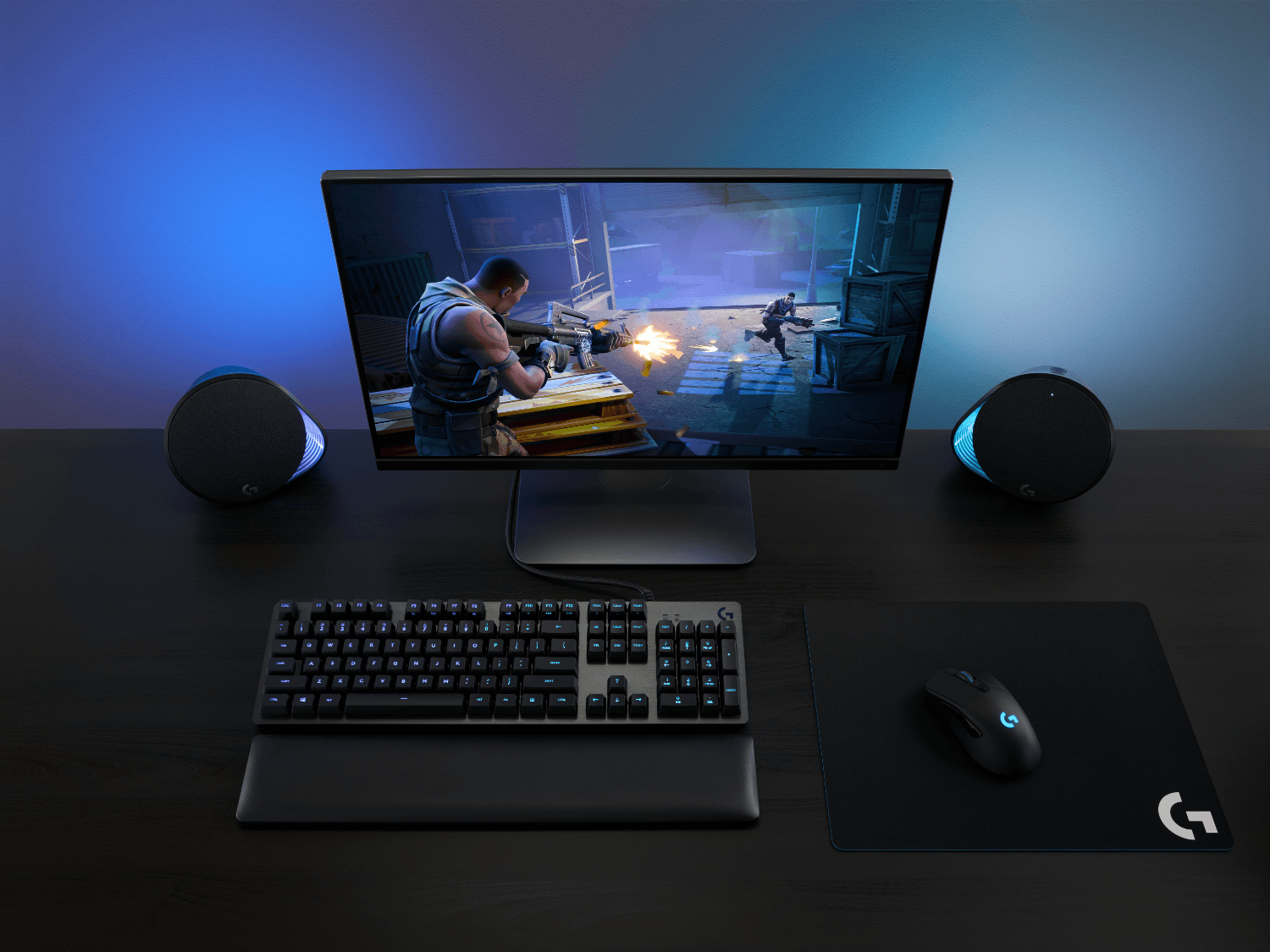 Una configuración de juego con monitor, teclado, ratón y altavoces. Una escena de videojuego en pantalla.