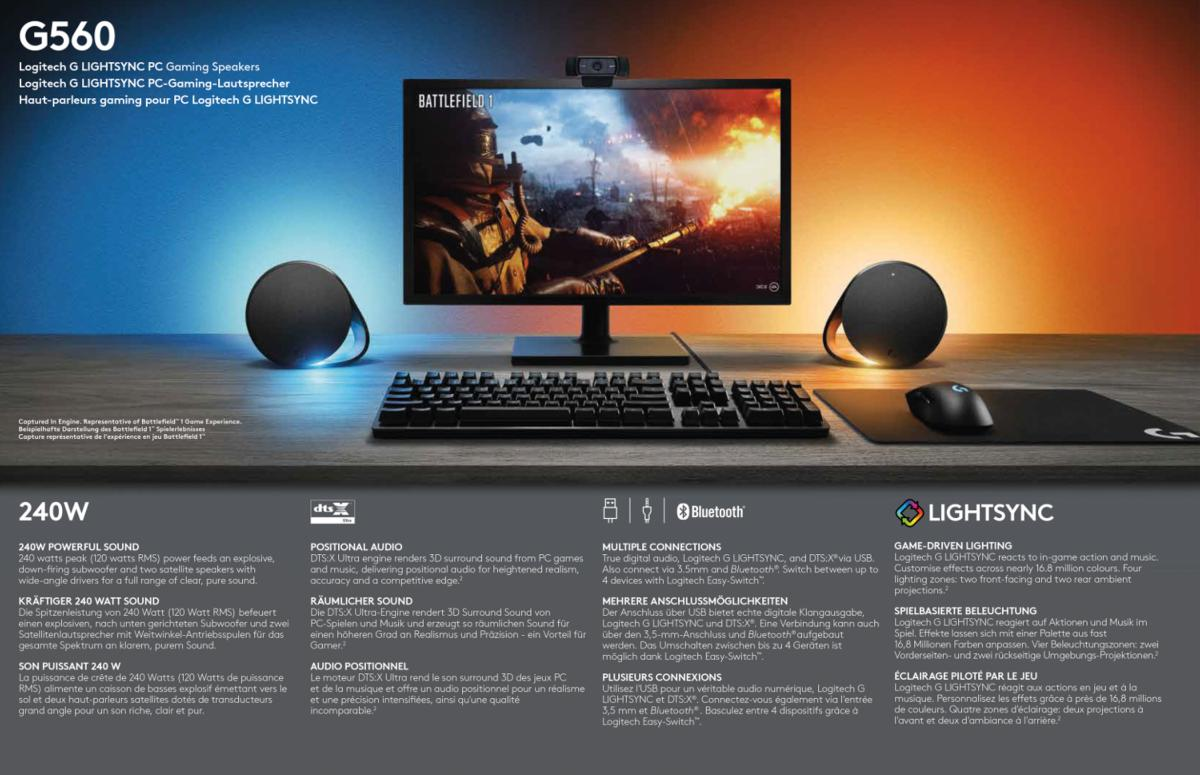 Altavoces gaming con pantalla mostrando un juego. Teclado, ratón y altavoces en un escritorio.