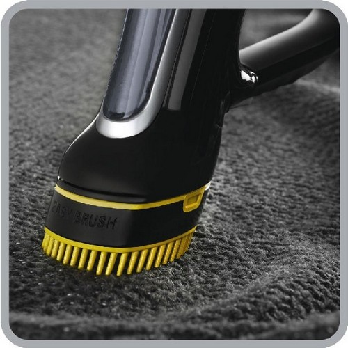 Primer plano de un cabezal de vaporizador de ropa negro con cerdas amarillas sobre tela gris.