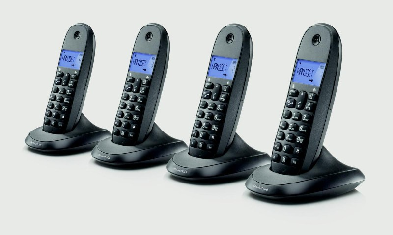 Cuatro teléfonos inalámbricos negros en bases, cada uno con pantalla, fondo claro.