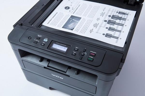 Impresora Brother negra con papel con gráficos y texto. Botones al frente.