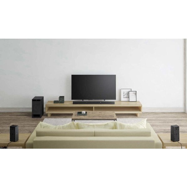 Sala de estar con TV, barra de sonido, subwoofer, altavoces, sofá y alfombra.
