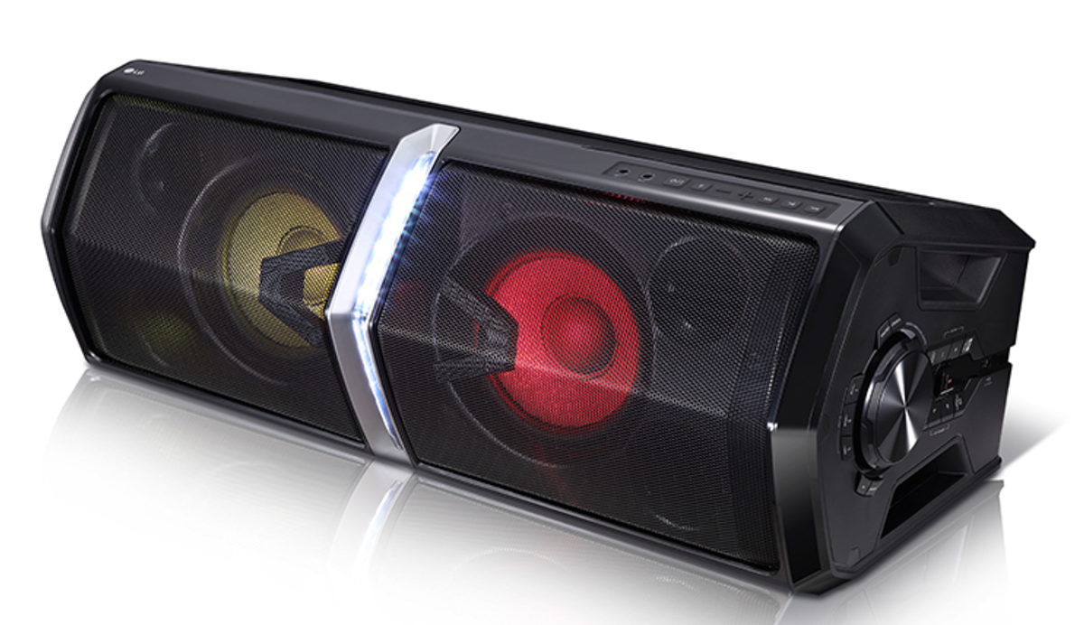 Altavoz LG negro con rejillas y luces. Dos luces amarillas y rojas. Detalles plateados. Fondo blanco.
