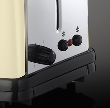Primer plano de una tostadora color crema con controles, incluido un dial de dorado.