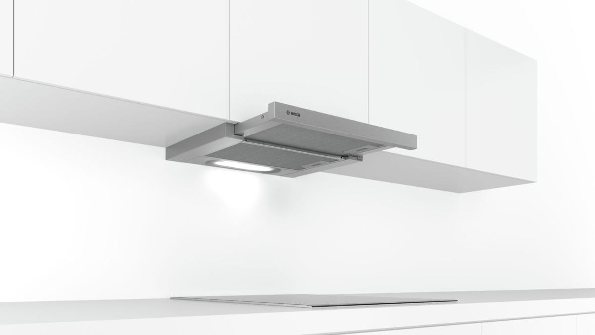 Cocina con encimera blanca y armarios superiores. Hay una campana extractora Bosch instalada.