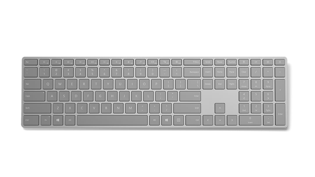 Teclado Microsoft gris con diseño completo, incluyendo teclado numérico, aislado sobre fondo blanco.