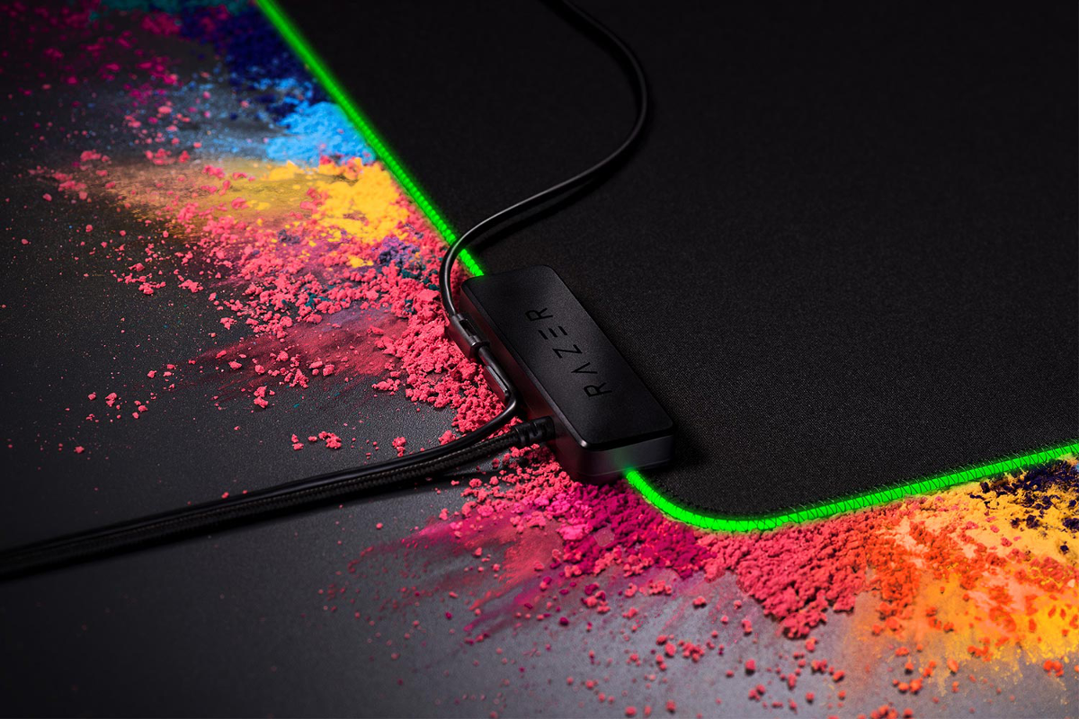 Tapis de souris noir avec des bords vert néon. Logo Razer et adaptateur noir. Art de poudre coloré autour.